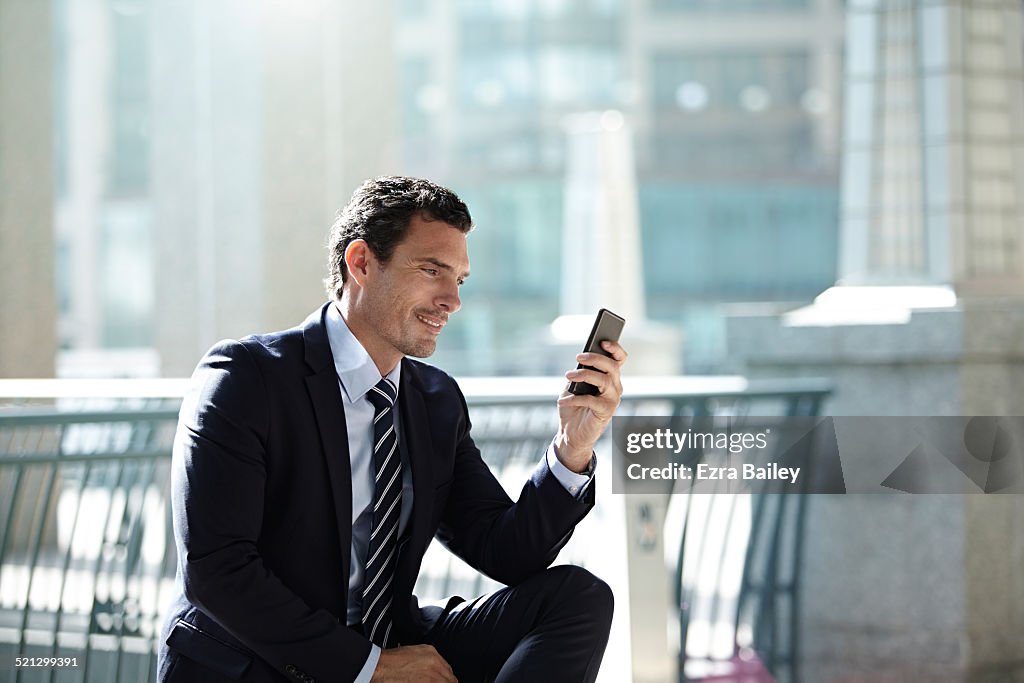 A businessman reading emails on his mobile phone..