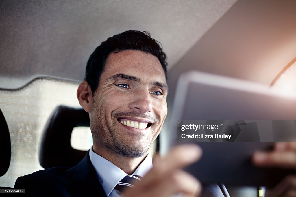 A businessman using a digital tablet in a taxi.