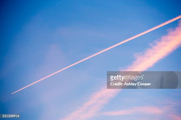 vapor trails lit by the setting sun over ambleside, cumbria, uk. - sunset contrail stock pictures, royalty-free photos & images