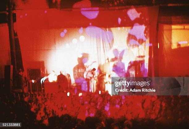 View from the back of the venue showing the crowd at the Roundhouse watching Pink Floyd perform in front of a psychedelic light show projection,...