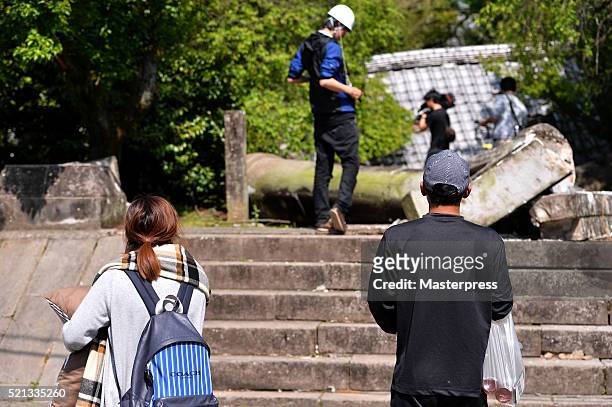 The evacuees look on as the TV crew films the damage a day after the 2016 Kumamoto Earthquake on April 15, 2016 in Mashiki, Kumamoto, Japan. As of...