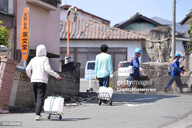 Locals carry water cases a day after the 2016 Kumamoto Earthquake on April 15, 2016 in Mashiki, Kumamoto, Japan. As of April 15 morning, at least...