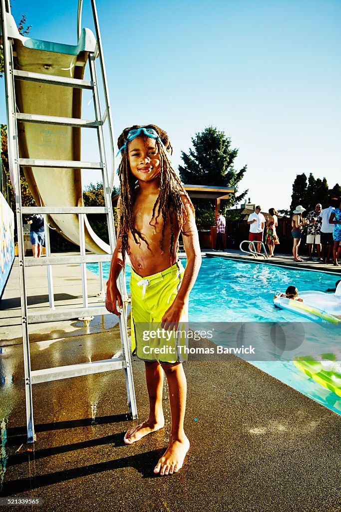 Young boy in swimsuit next to pool during party