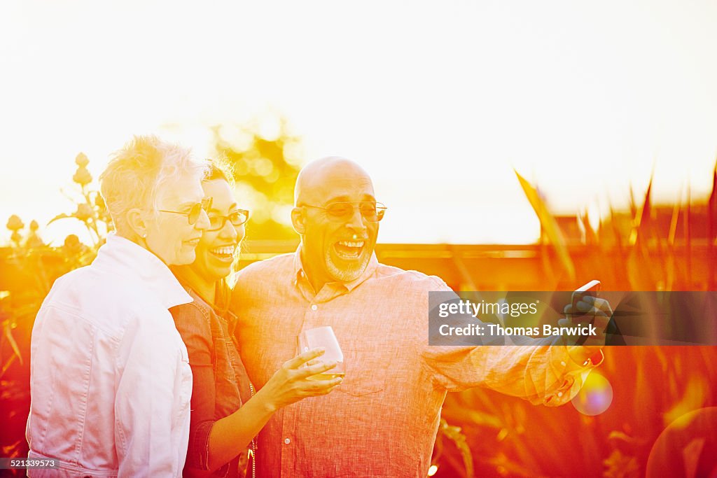 Three mature friends at party taking self portrait