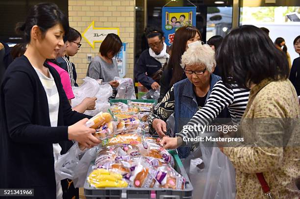 People receive relief supplies at the evacuation center a day after the 2016 Kumamoto Earthquake at the Mashiki Town Hall on April 15, 2016 in...