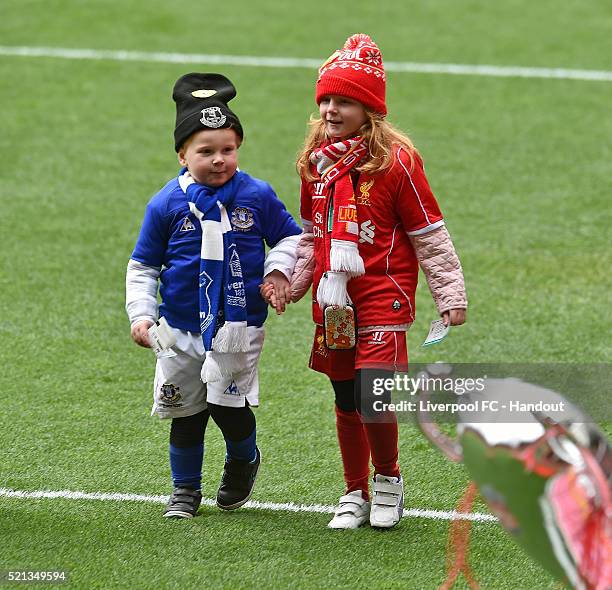 In this handout photograph provided by Liverpool FC, a young Liverpool fan holds hands with a young Everton fan as they pay their respects during the...