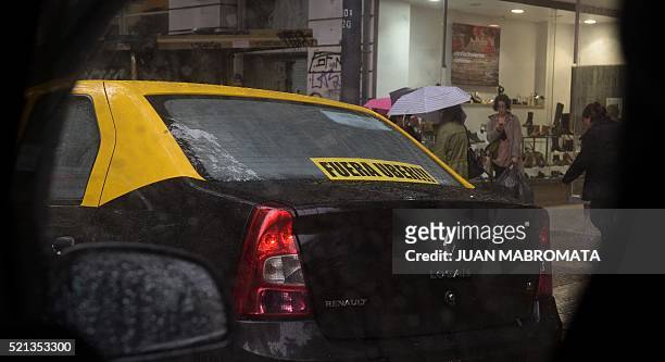 Cab displaying a banner reading in Spanish "Get out Uber", is seen after a protest against Uber in Buenos Aires on April 15, 2016. Uber started...