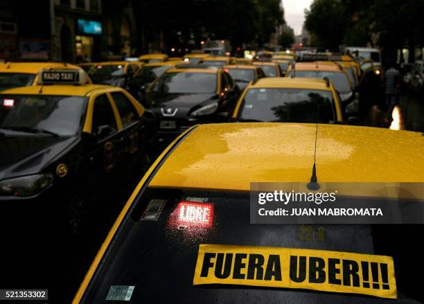 Cab displaying a banner that reads in Spanish "Get out Uber" blocks, among others, Callao avenue during a protest against Uber in Buenos Aires on...