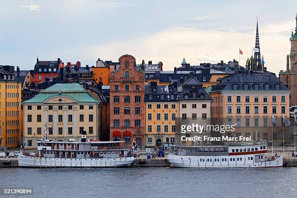 boats at the quay of skeppsbron and houses in the old town, gamla stan, stockholm, sweden - stockholm old town stock pictures, royalty-free photos & images