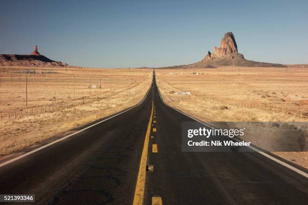 Two lane blacktop highway runs straight through the desert near Monument Valley Navajo Tribal Parkon the Arizona/Utah border in the southwestern USA.