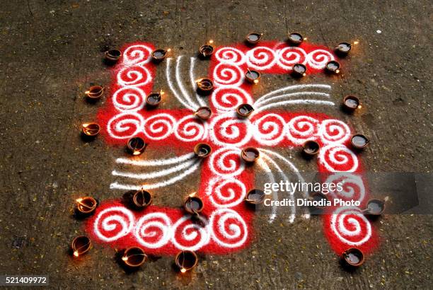 rangoli floor design with swastik and lighted clay lamps during diwali deepawali festival - rangoli stock pictures, royalty-free photos & images