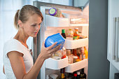 Pretty, young woman in her kitchen by the fridge