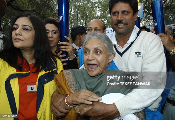 Delhi Chief Minister Sheila Dixit is hugged by former Indian cricketer Kapil Dev as they take part in the "Light for Life" walk aimed at raising...