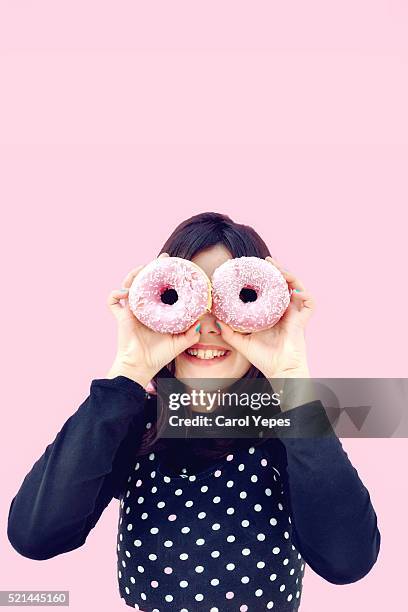 girl with pink donuts in front of her eyes - fat people eating donuts foto e immagini stock