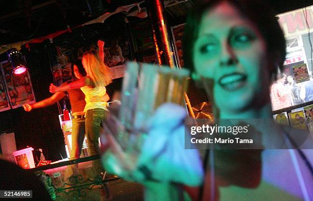 Revelers dance in a bar as a waitress carries shots of alcohol during Mardi Gras festivites February 6, 2005 in New Orleans, Louisiana. Festivities...