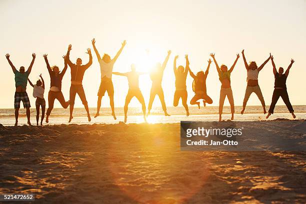 young people jumping at the beach of st.peter-ording in germany - jumping sun bildbanksfoton och bilder