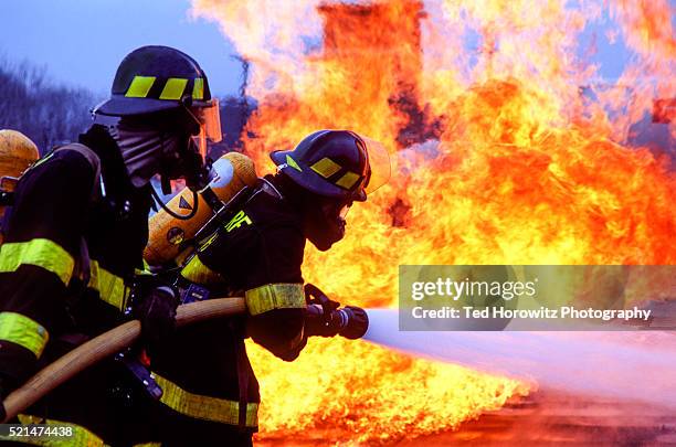 firemen fighting blaze with hose. - fire hose stock pictures, royalty-free photos & images