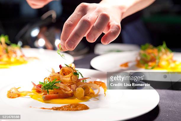 hand garnishing a plate of poached lobster with carrot crue-cuite - ristorante foto e immagini stock