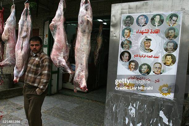 Palestinian man stands at the entrance to a butcher shop with election posters next to it in Abu Dis Sunday January 22 2006. Palestinian Authority...