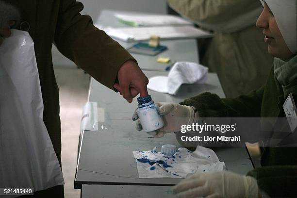 Palestinian marks his finger with ink as he is to cast his ballot at a polling station in the West Bank town of Hebron, Wednesday, January 25, 2006....