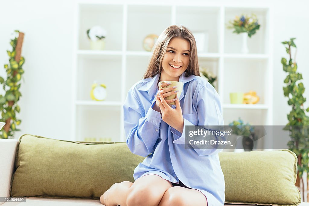 Ritratto di allegro donna bere il caffè a casa e sorridente