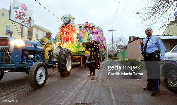 Police officer looks on as a float passes during the historic Proteus parade, founded in 1882, during Mardi Gras festivites February 7, 2005 in New...