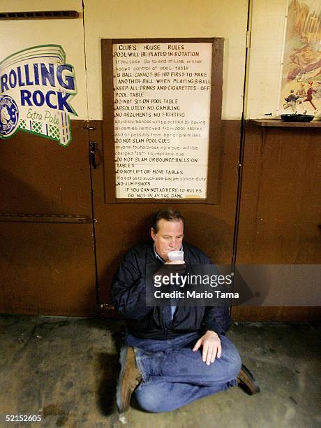 Man sits in a bar beneath a "Club's House Rules" handwritten sign during Mardi Gras festivites February 7, 2005 in New Orleans, Louisiana....