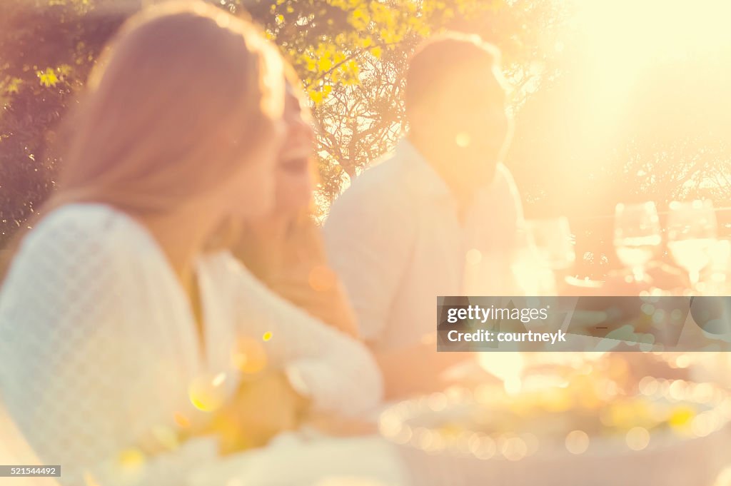 Defocussed group of young people eating outdoors.