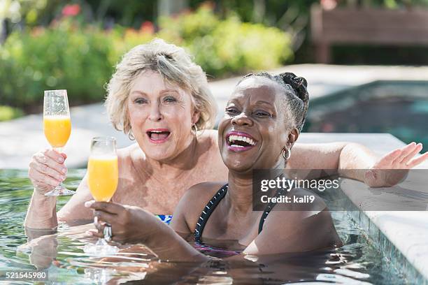two mature women enjoying cocktail in swimming pool - hot tub party stock pictures, royalty-free photos & images