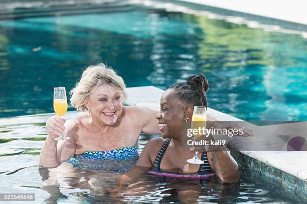 two mature women enjoying cocktail in swimming pool - hot tub party stock pictures, royalty-free photos & images
