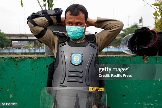 Member of the civil service police unit members puts on a protection mask during the demolition of Kalijodo red-light district. Bulldozers started...
