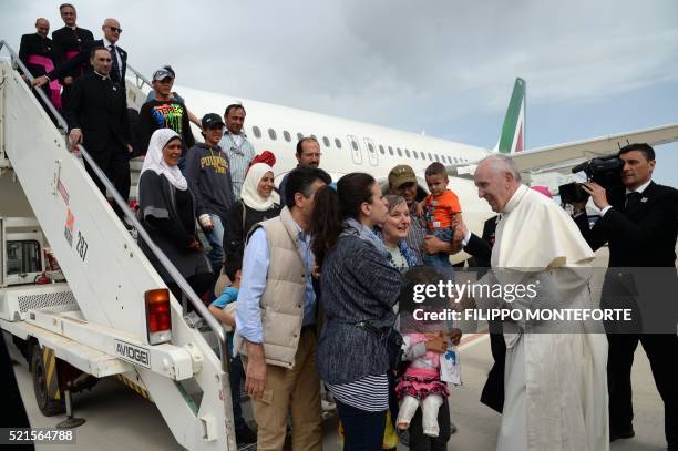 Pope Francis welcomes a group of Syrian refugees after landing at Ciampino airport in Rome following a visit at the Moria refugee camp on April 16,...