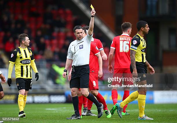 Referee Dean Whitestone shows a yellow card to Joss Labadie of Dagenham & Redbridge during the Sky Bet League Two match between Leyton Orient and...