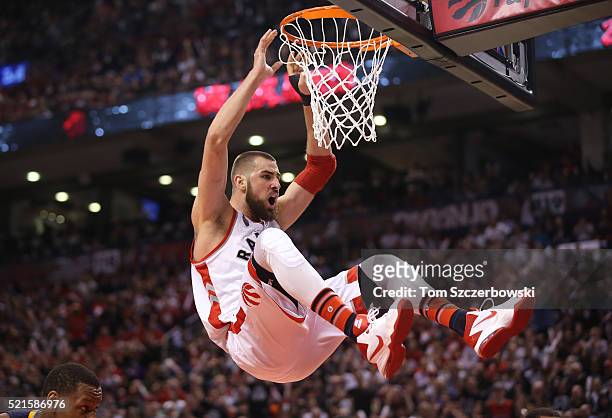 Jonas Valanciunas of the Toronto Raptors holds on to the rim after dunking the ball against the Indiana Pacers in Game One of the Eastern Conference...