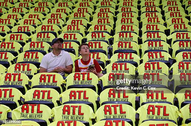 Two fans sit in the stands awaiting Game One of the Eastern Conference Quarterfinals during the 2016 NBA Playoffs between the Atlanta Hawks and...