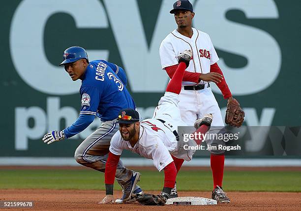 Dustin Pedroia of the Boston Red Sox turns a double play as Ezequiel Carrera of the Toronto Blue Jays reacts at second base in the eighth inning...