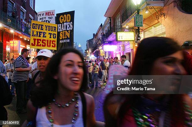 Women walk past people holding religious signs on Bourbon Street during Mardi Gras festivities February 8, 2005 in New Orleans, Louisiana. Mardi Gras...