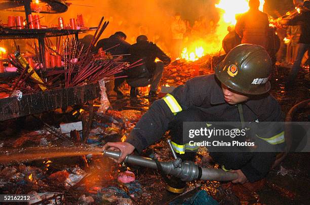 Firemen put out burning incense to prevent a fire after a praying ceremony to welcome the Chinese New Year in the early hours of February 9, 2005 in...