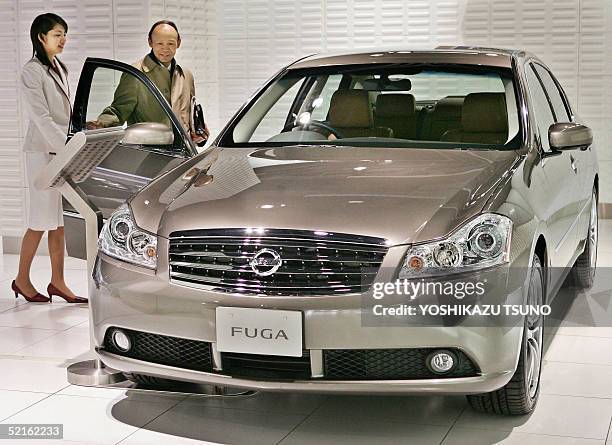 Customer checks a luxury sedan "Fuga" of Japan's auto giant Nissan Motor at the company's showroom in Tokyo, 09 February 2005. Nissan Motor said its...