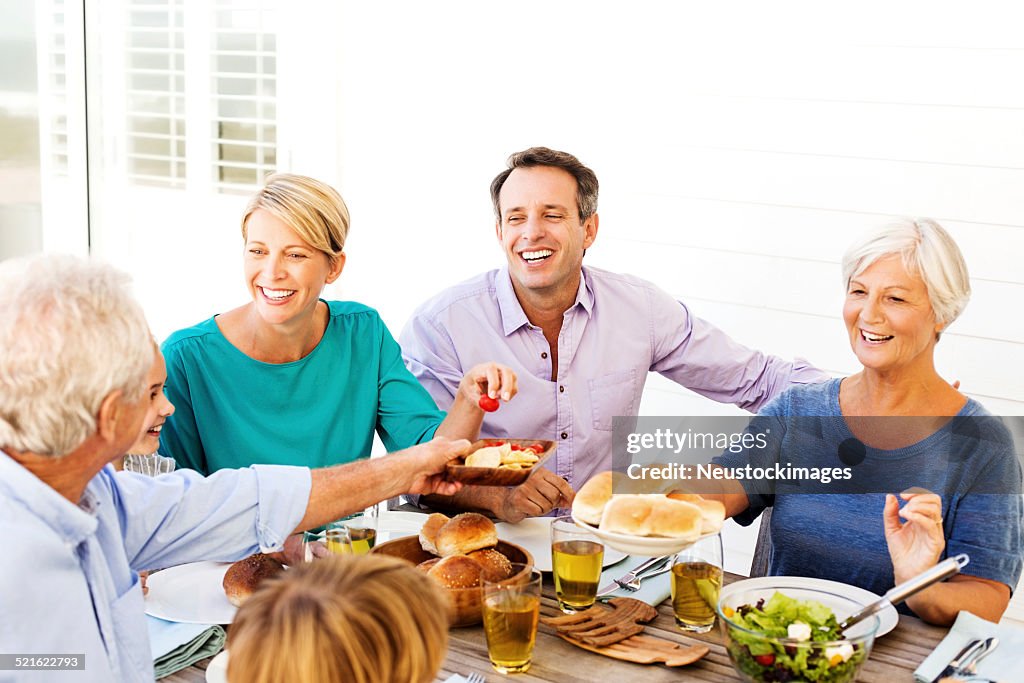 Multi-Generation Family Enjoying Meal At Table On Patio