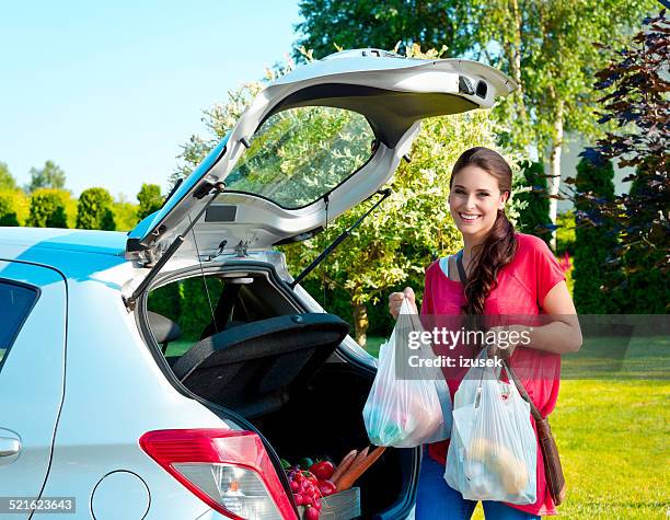 young woman standing outdoor, holding shopping bags - shopping bags car boot stock pictures, royalty-free photos & images