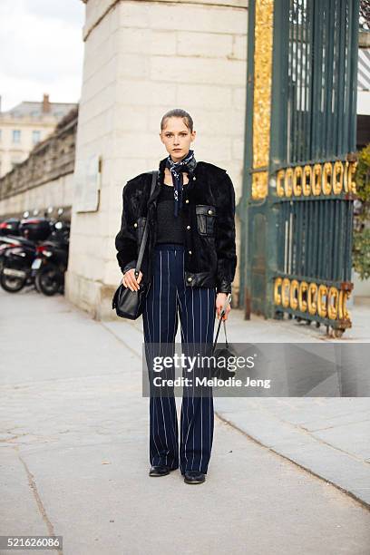 Model Maria Zakrzewska wears a blue bandana around her neck, a black cropped fur jacket, and high waisted flared blue striped pants after the...