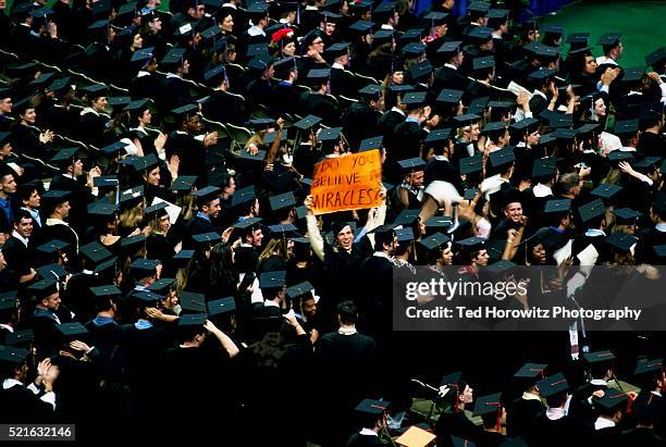 graduate holding sign - graduation crowd - fotografias e filmes do acervo