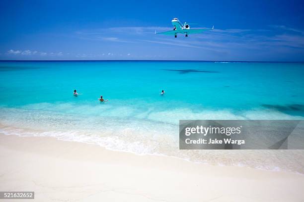 airplane over beach during landing st. maarten - isla de san martín fotografías e imágenes de stock