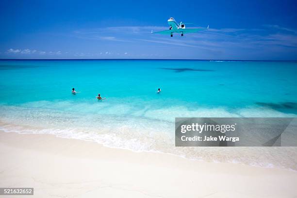 airplane over beach during landing st. maarten - sint maarten stock pictures, royalty-free photos & images