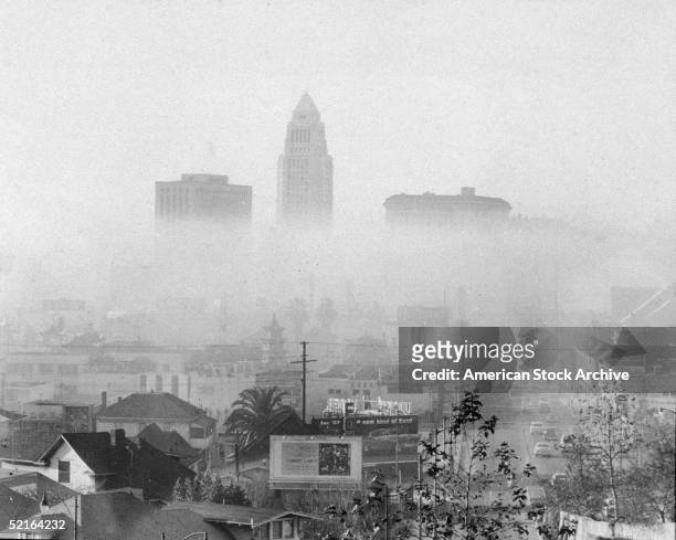 Photo shows the skyline of downtown Los Angeles including the city hall and the United States Courthouse , and Hall of Justice shrouded and obscured...