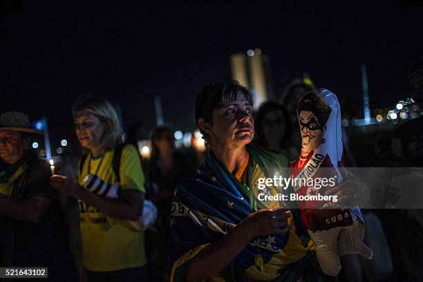 Protester holds a candle and an inflatable figure in the likeness of Dilma Rousseff, Brazil's president, during a demonstration against Rousseff...