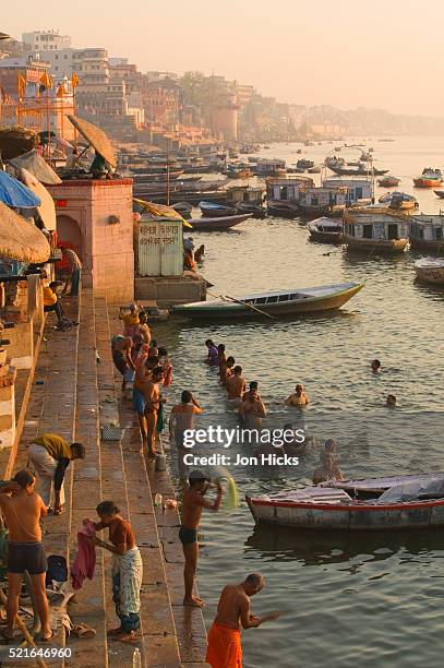 people bathing at the ghats at sunrise - ganges stockfoto's en -beelden