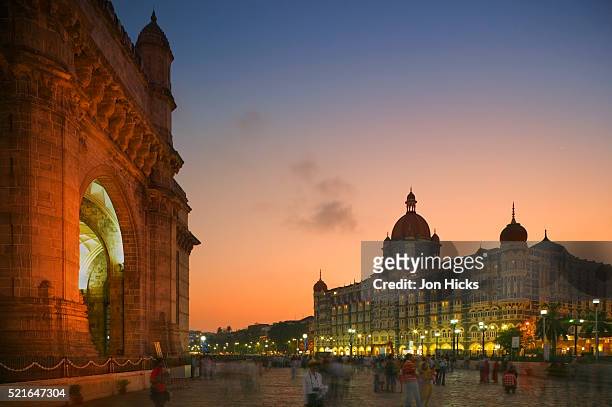 people strolling between the gateway of india and the taj mahal palace hotel - gateway to india stock-fotos und bilder