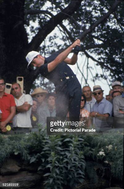 South African professional golfer Gary Player swings a club and hits the ball on the fourteenth hole in front of spectators at the US Open golf...